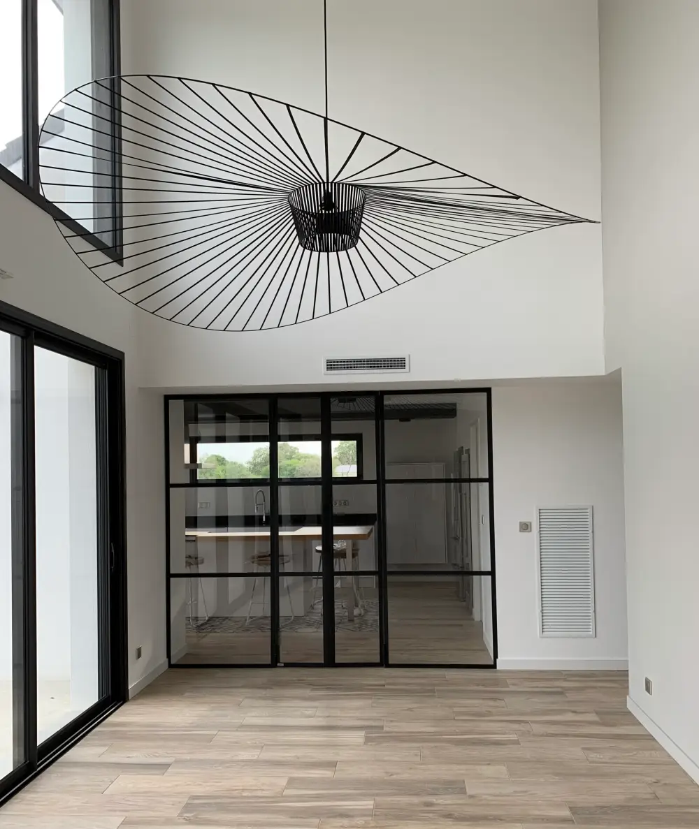 Installation d’une suspension lumineuse design dans une pièce de vie avec plafond haut